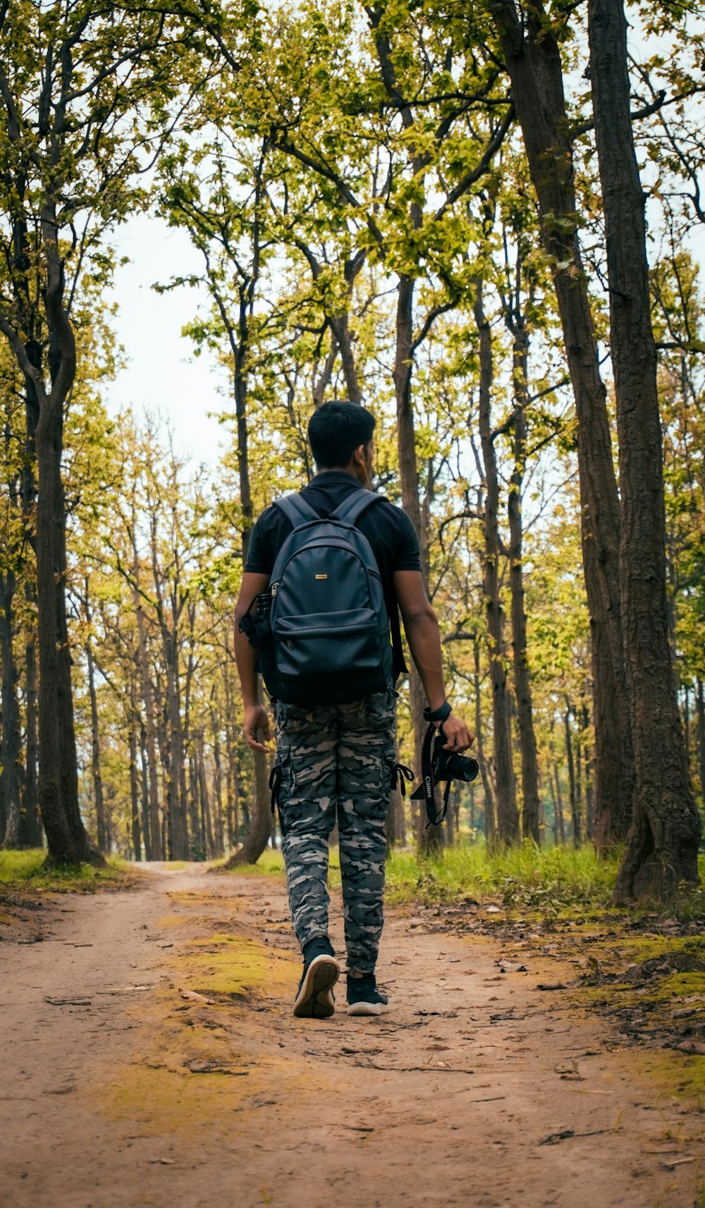 a man walking down a dirt road in the woods