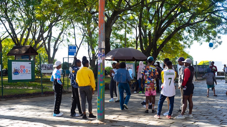 A group of diverse people playing sports and sharing books in a sunny community park.