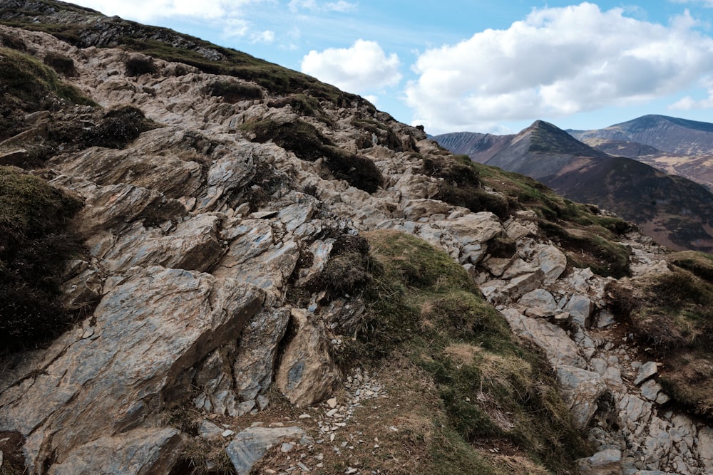 a rocky mountain with grass growing on top of it