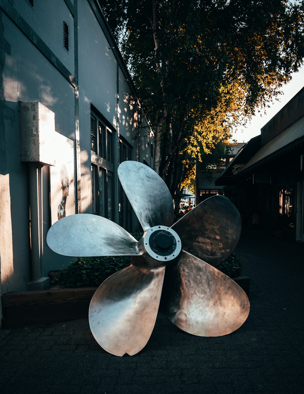 a large metal propeller sitting in front of a building