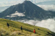 a group of people hiking up a grassy hill