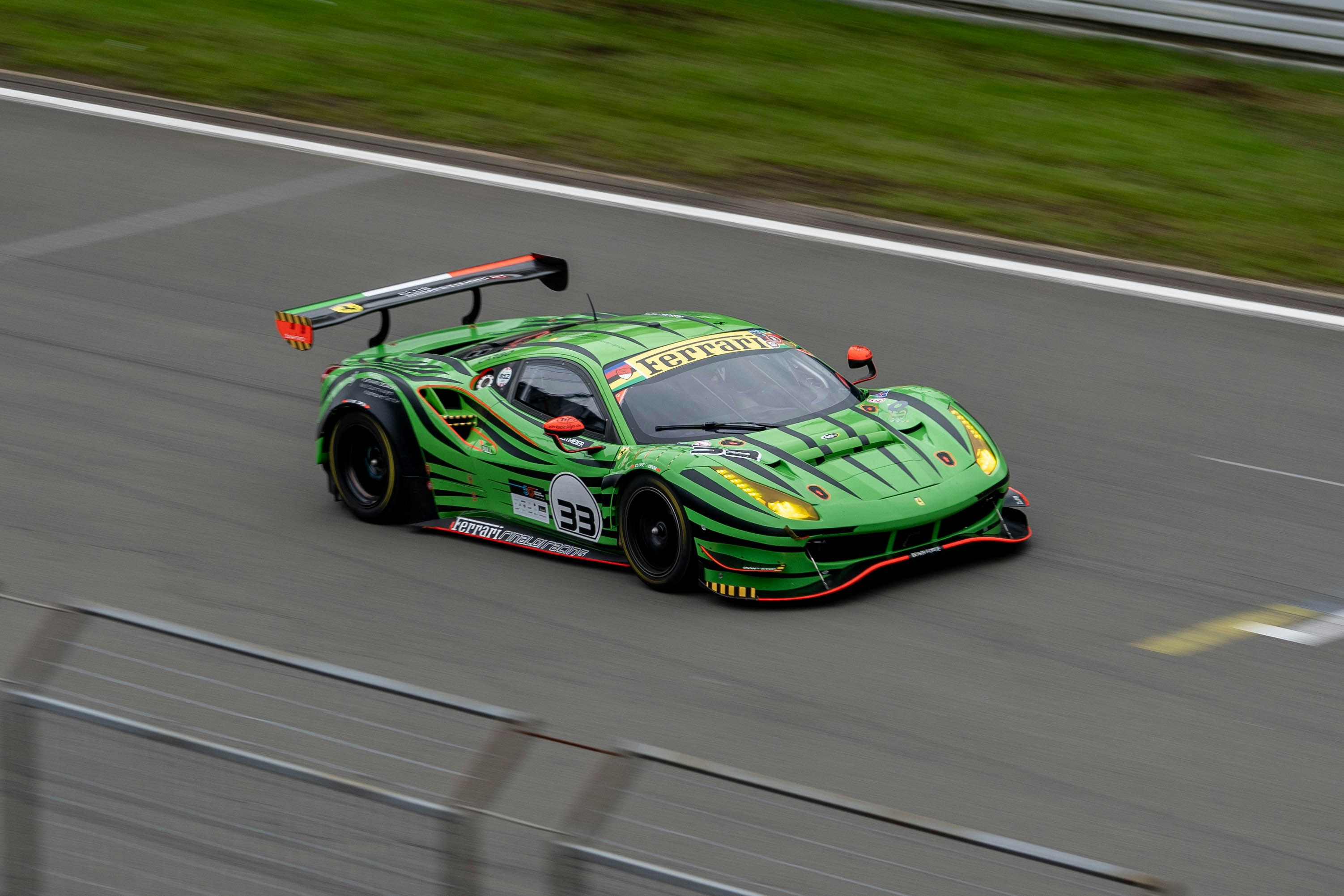 A green race car driving down a race track photo – Free Car Image on ...