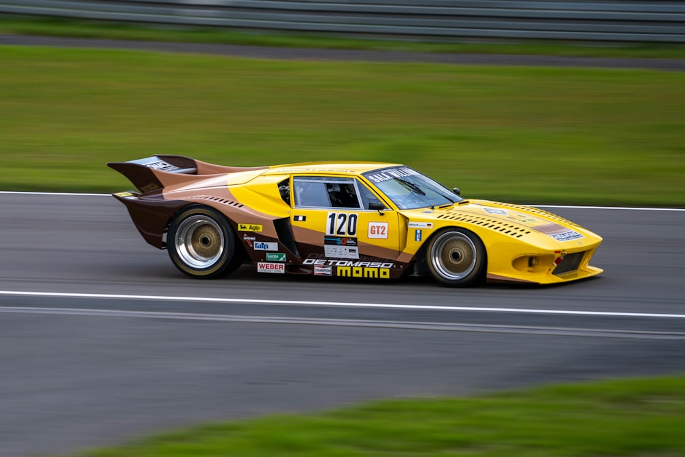 a yellow race car driving down a race track