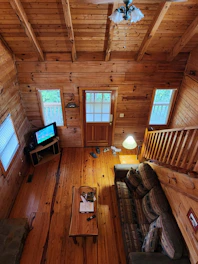 Interior of a cabin living room with a glowing fireplace and rustic wooden furniture.