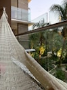 Balcony overlooking the sea with hammock and palm trees.