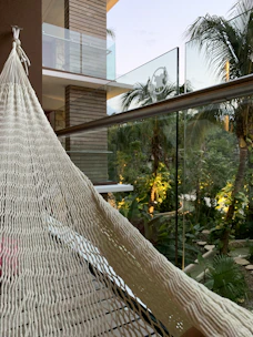 A cozy Bali villa patio with tropical plants and a hammock overlooking a serene sunset.