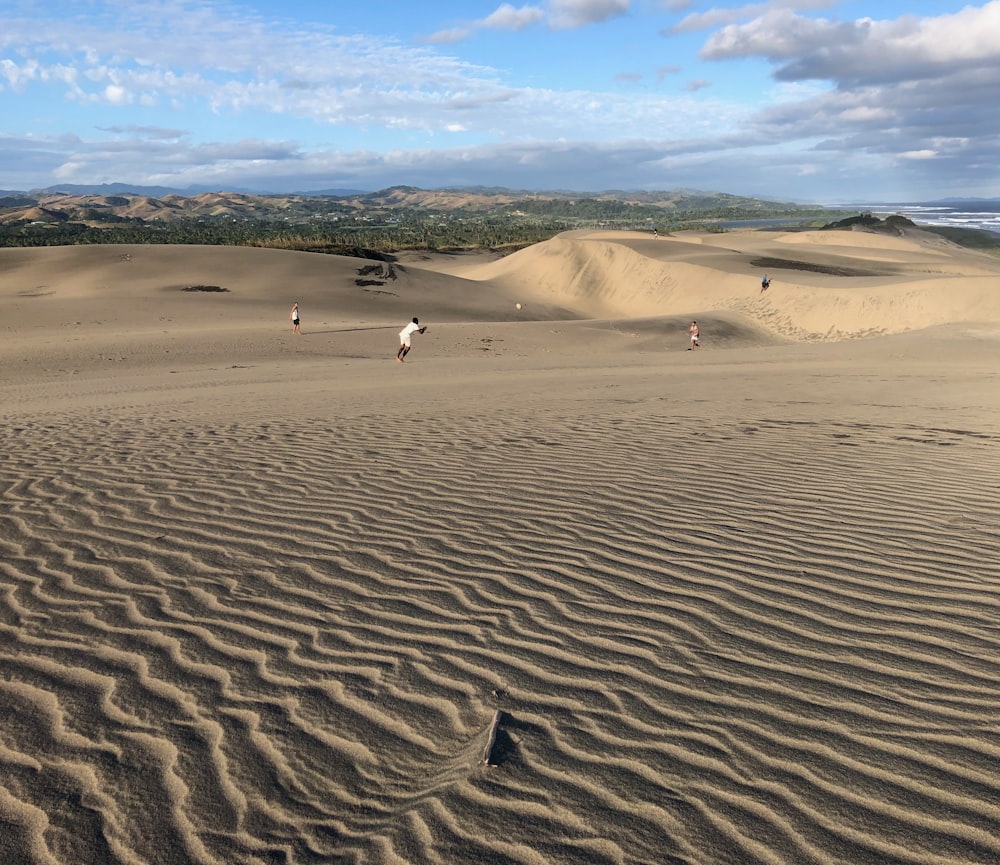 a group of people walking across a sandy beach