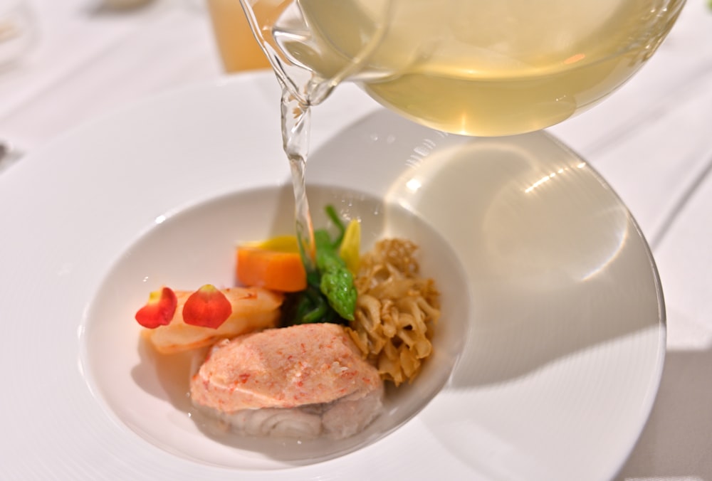 a white plate topped with meat and veggies next to a glass of wine