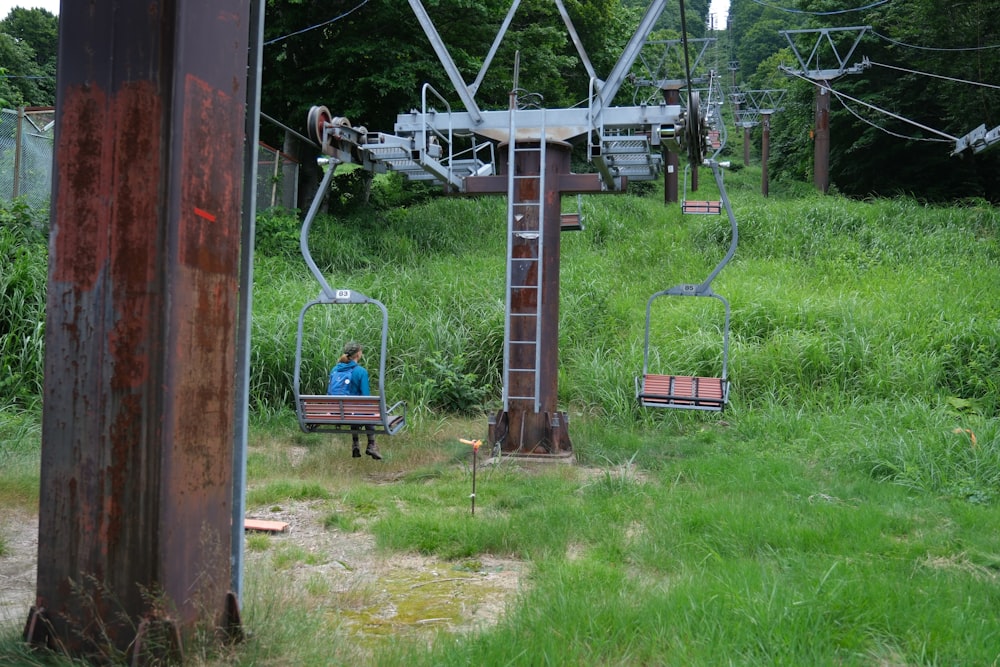 a person sitting on a chair lift in the grass