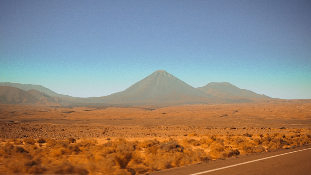 uma vista de um deserto com uma montanha ao fundo