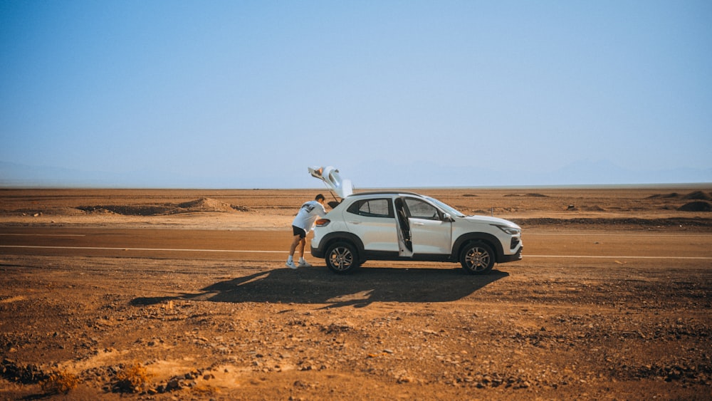 사막에서 하얀 차 옆에 서 있는 남자