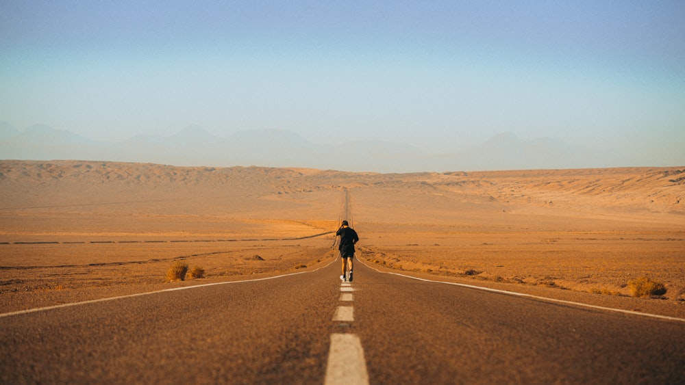 a person riding a skateboard down a desert road