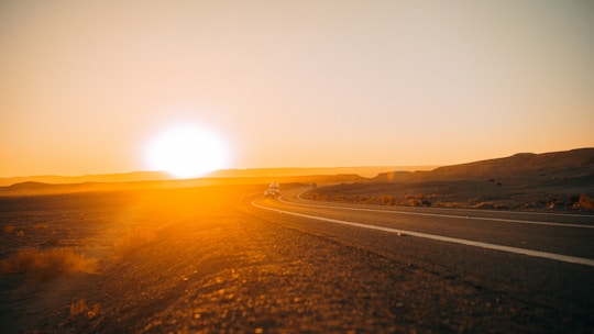 A scenic view of a classic American road stretching through a desert landscape at sunset.