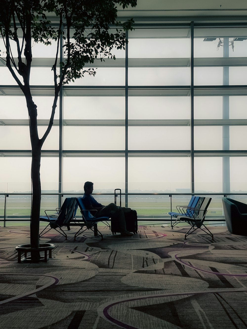 a man sitting in a chair next to a tree