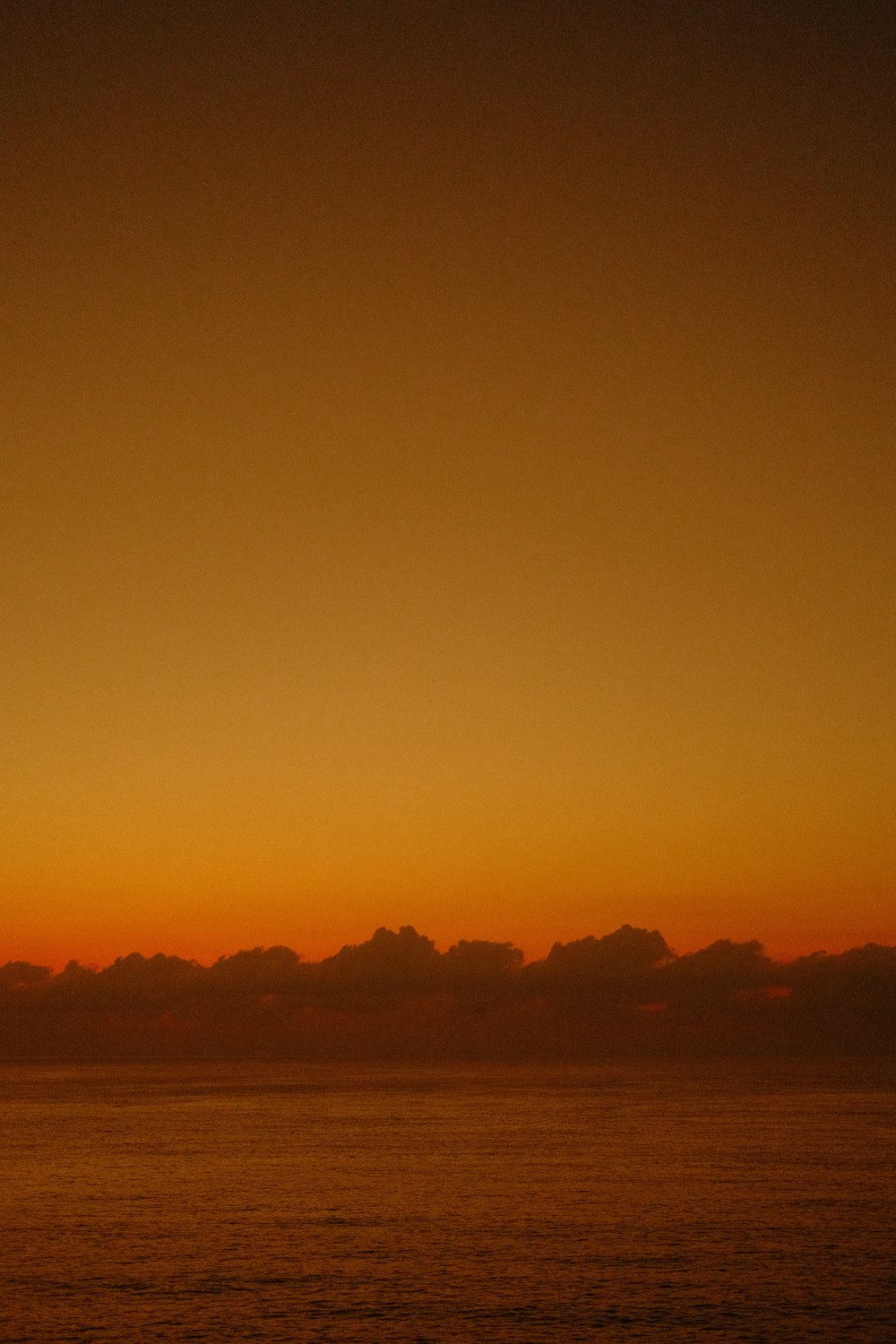 a plane flying over a body of water at sunset