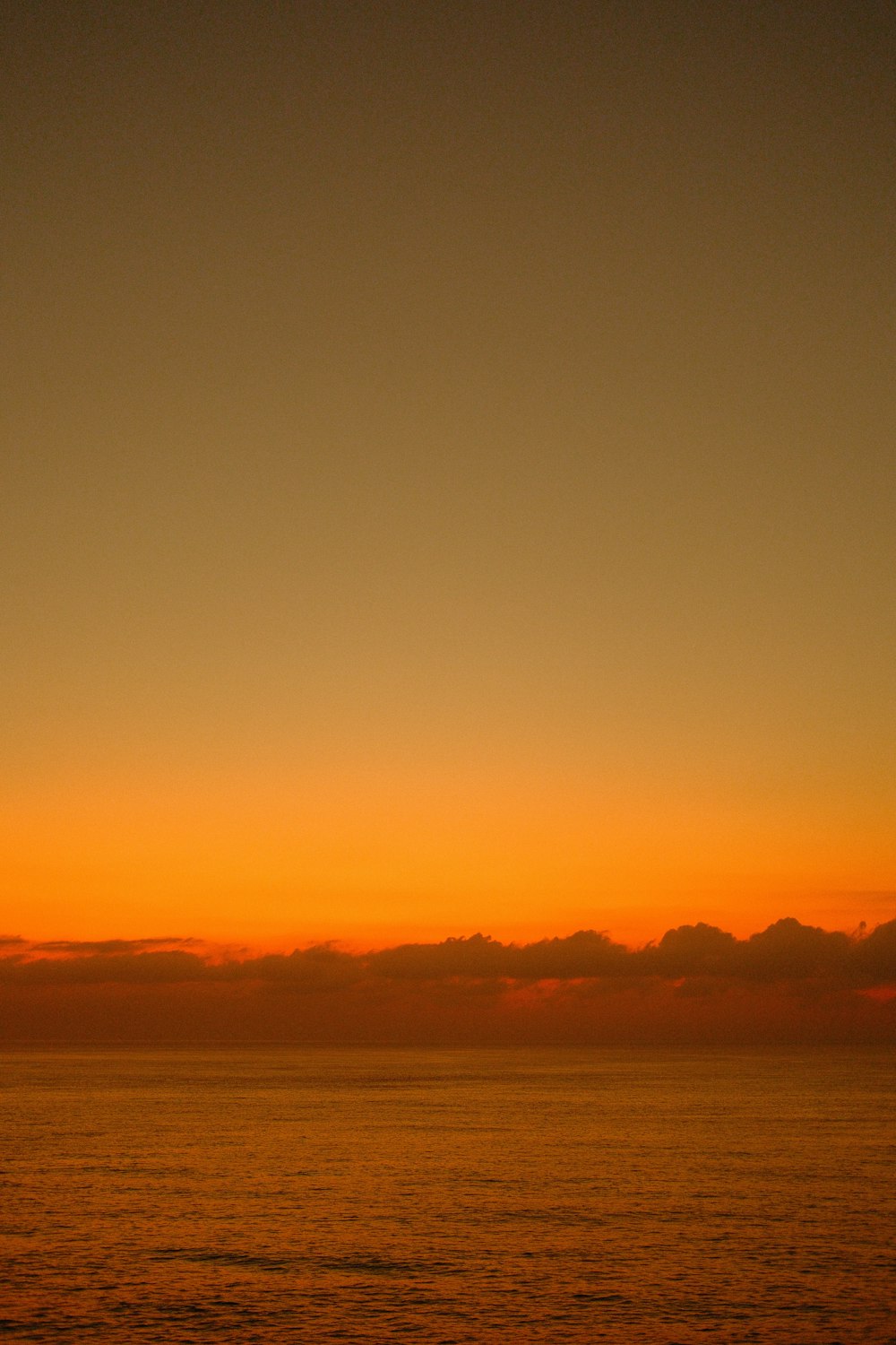 a plane flying over a body of water at sunset