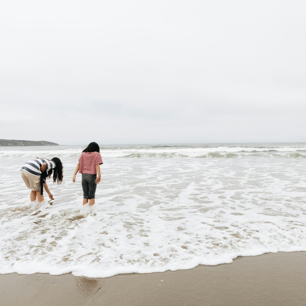 two girls are playing in the surf at the beach