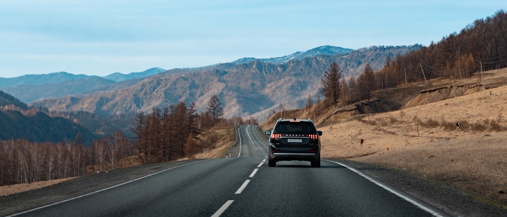 a car driving down a road with mountains in the background