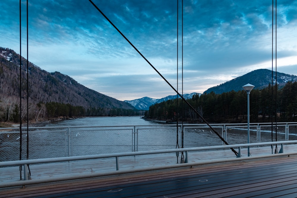 a wooden bridge over a river with mountains in the background