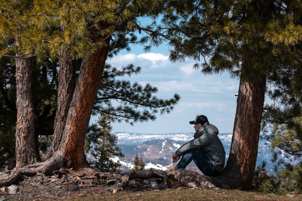 a man sitting on top of a hill next to trees