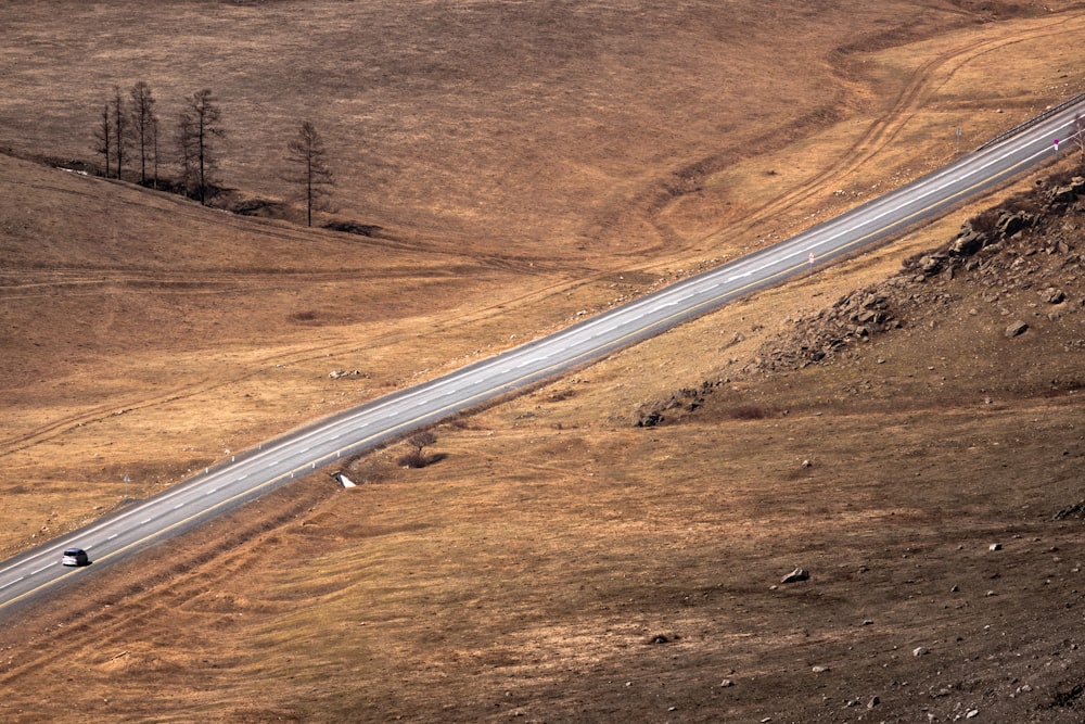 a truck driving down a road in the middle of a field