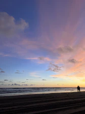 A serene beach sunset with a couple enjoying a peaceful moment together.