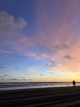A serene beach sunset with silhouettes of couples enjoying the moment together.