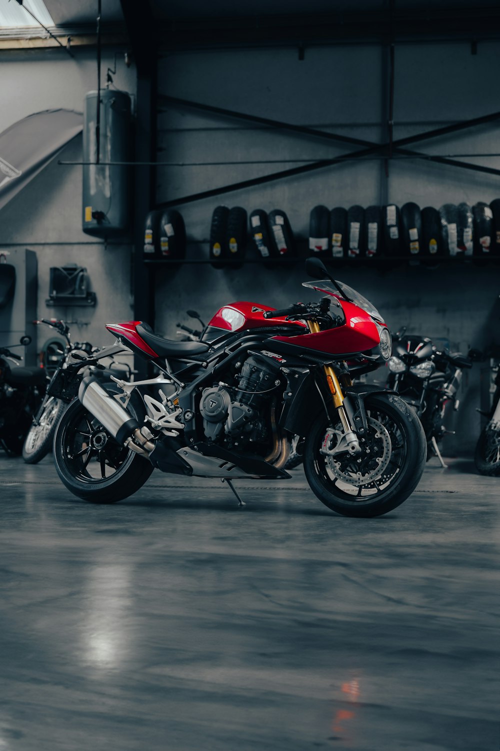 a red motorcycle parked in a garage next to other motorcycles