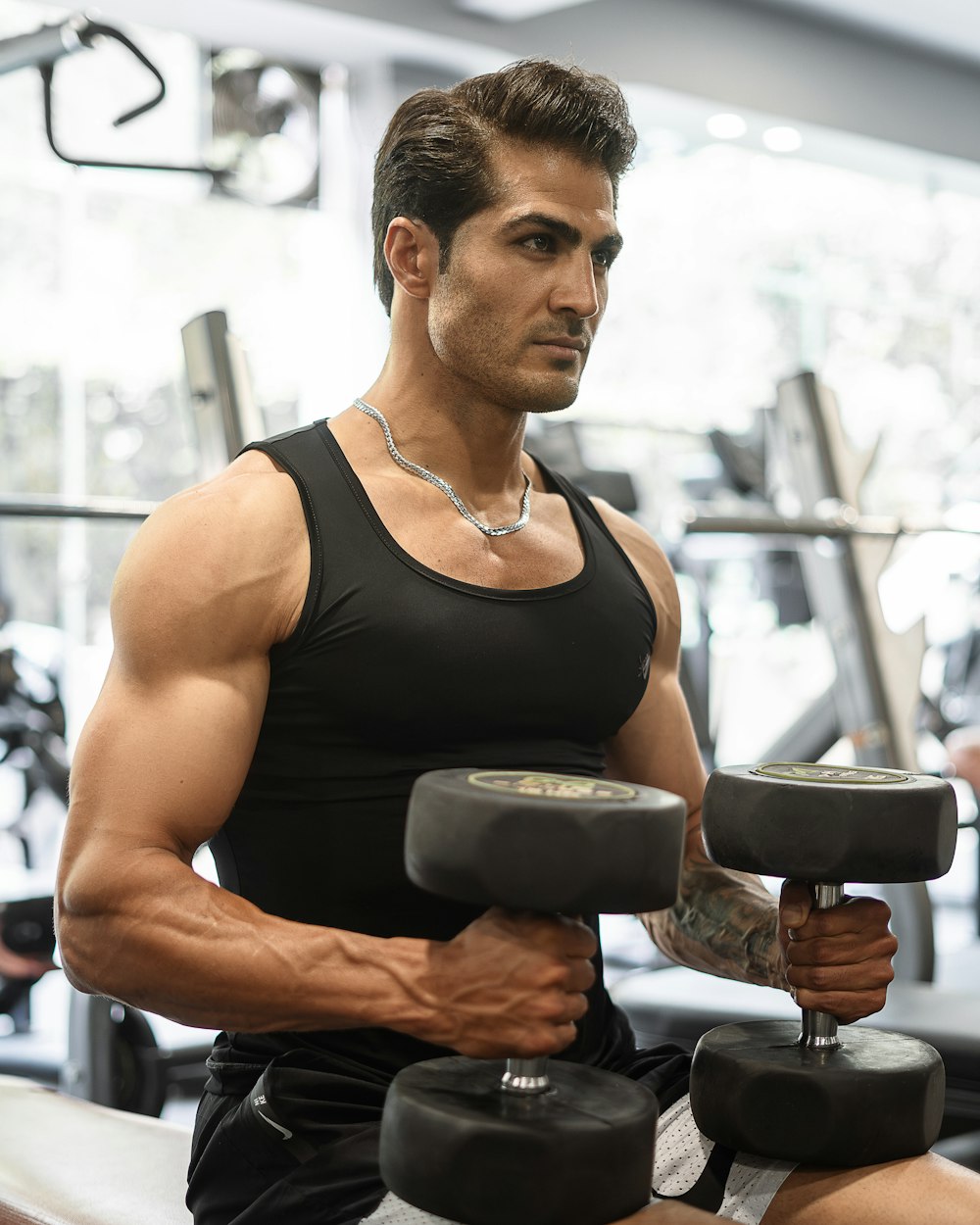 a man in a gym holding a pair of dumbs