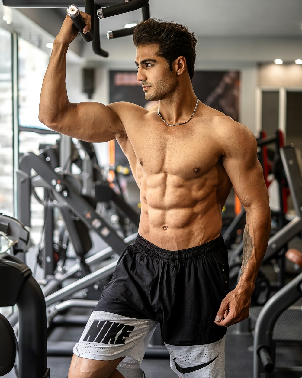 a shirtless man holding a barbell in a gym