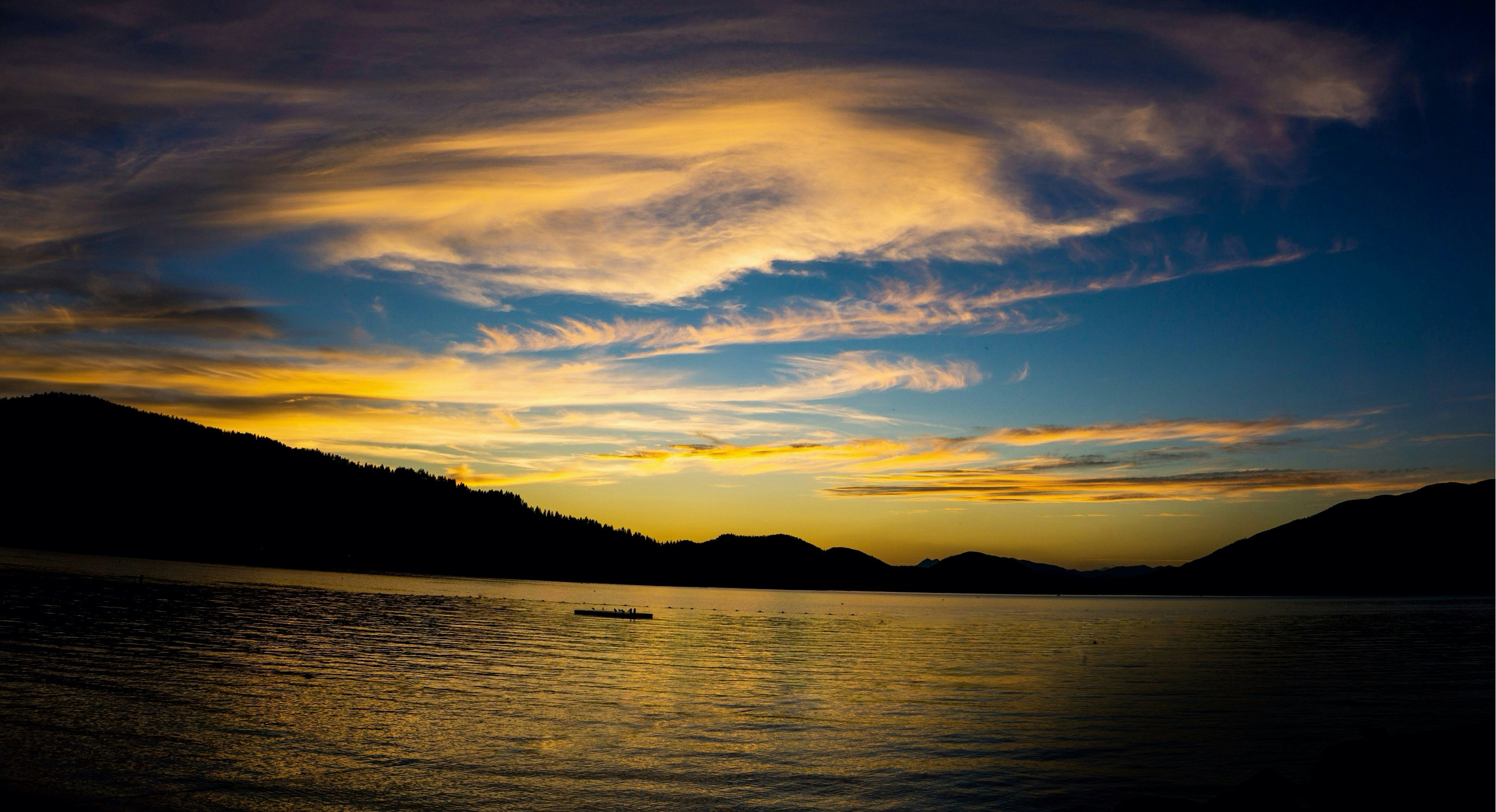 a boat floating on top of a lake under a cloudy sky