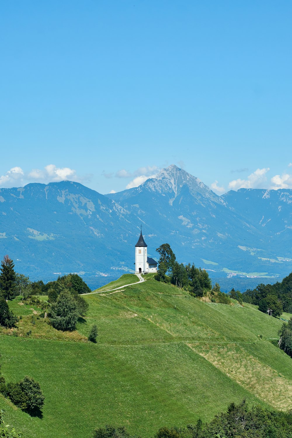 a church on a hill with mountains in the background