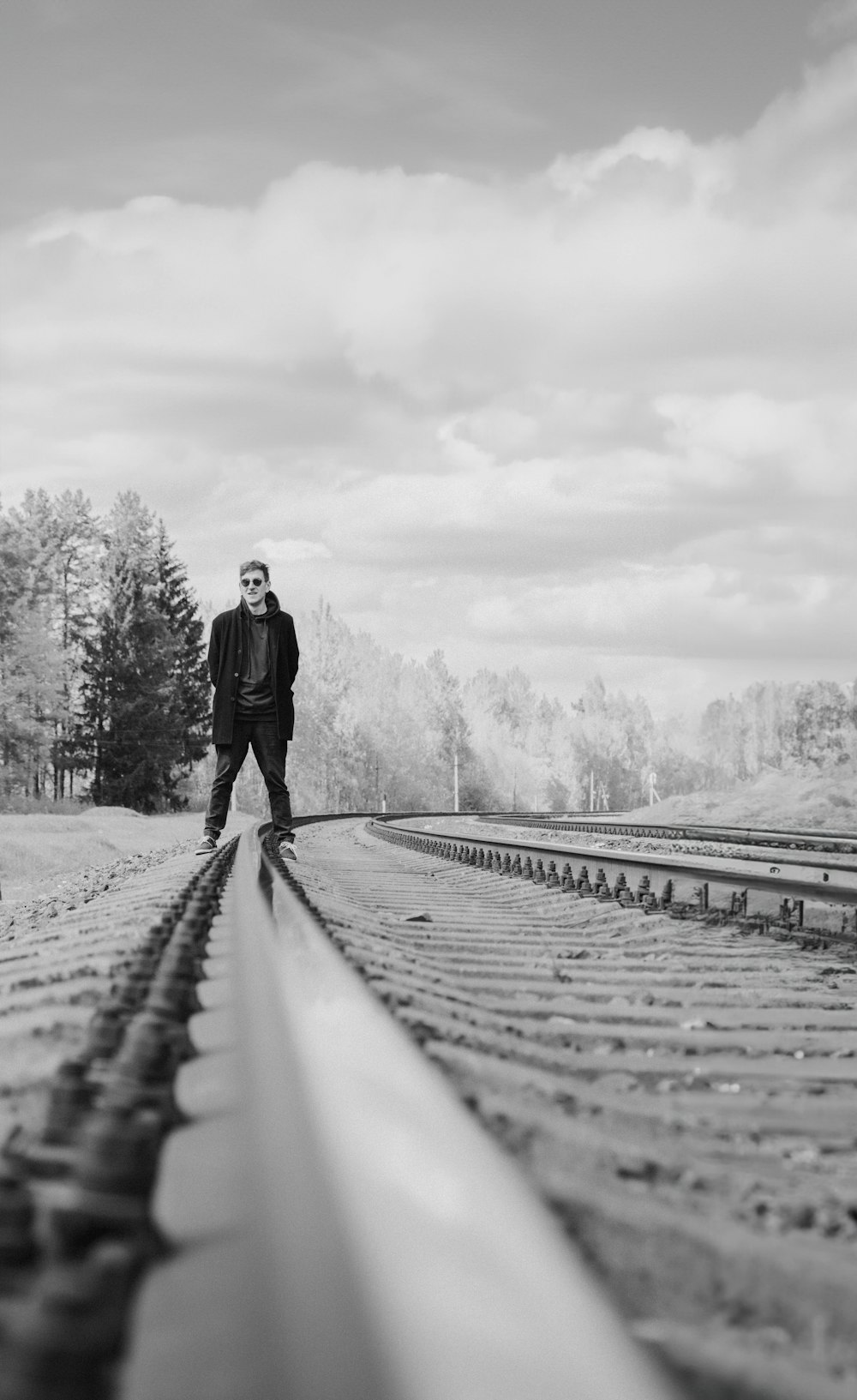 a man standing on a train track in a black and white photo