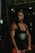 A muscular man is in a gym setting, wearing a black tank top with 'P&F Pharma' printed on it. He appears to be focused and strong, engaged in weightlifting.