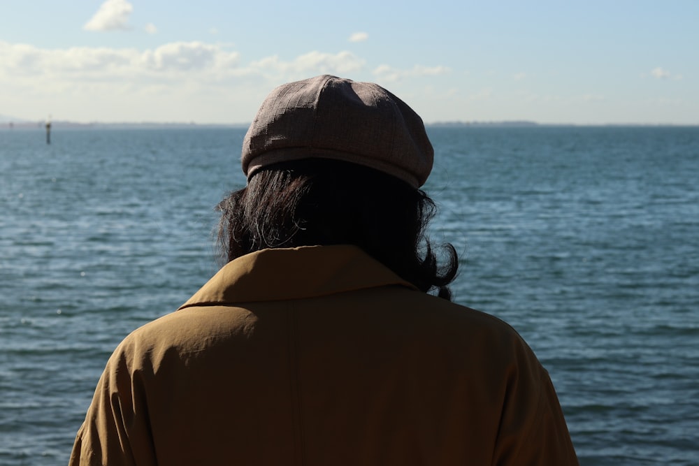 a person wearing a hat looking out at the ocean