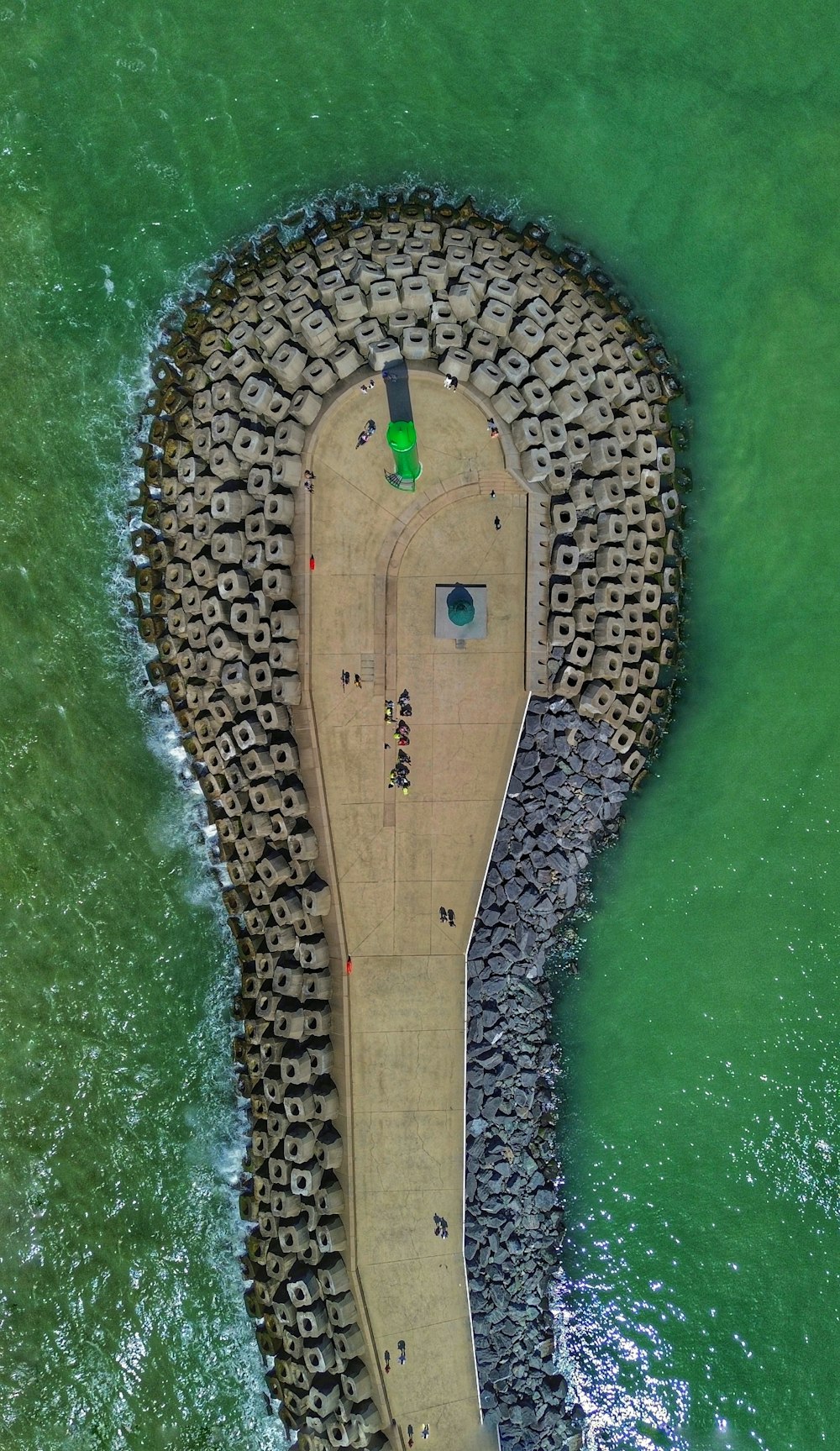 an aerial view of a pier with a green umbrella