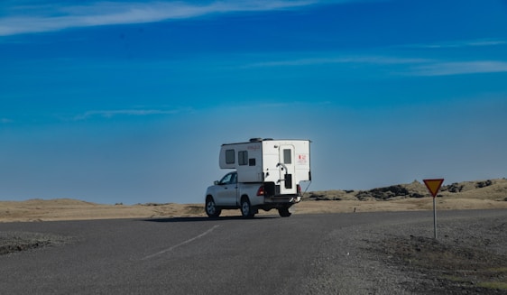 A sturdy tow truck hauling a camper trailer along a scenic country road.