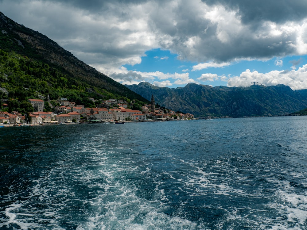 a body of water with houses and mountains in the background