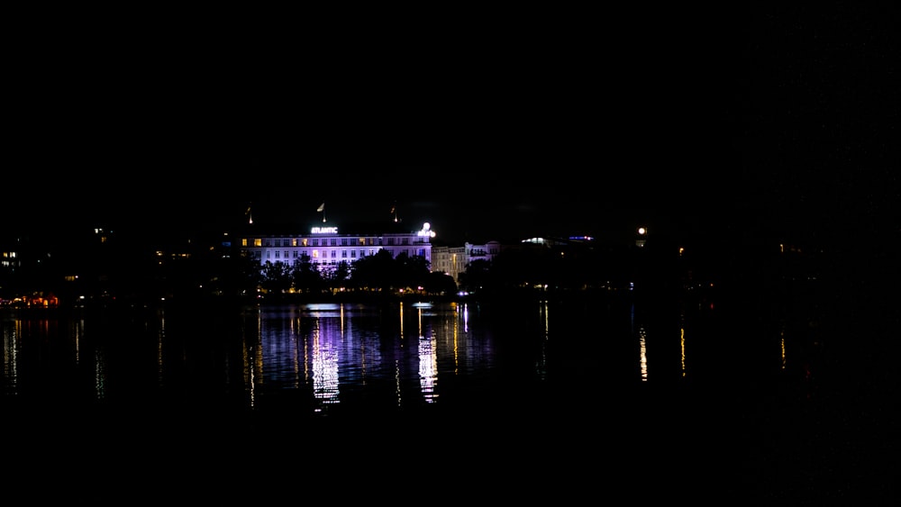 Ein großes Gebäude, das nachts auf einem See sitzt