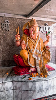 Golden statue of Ganesha with marigold garlands in a temple corner.
