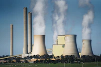 smoke billows from the cooling towers of a power plant