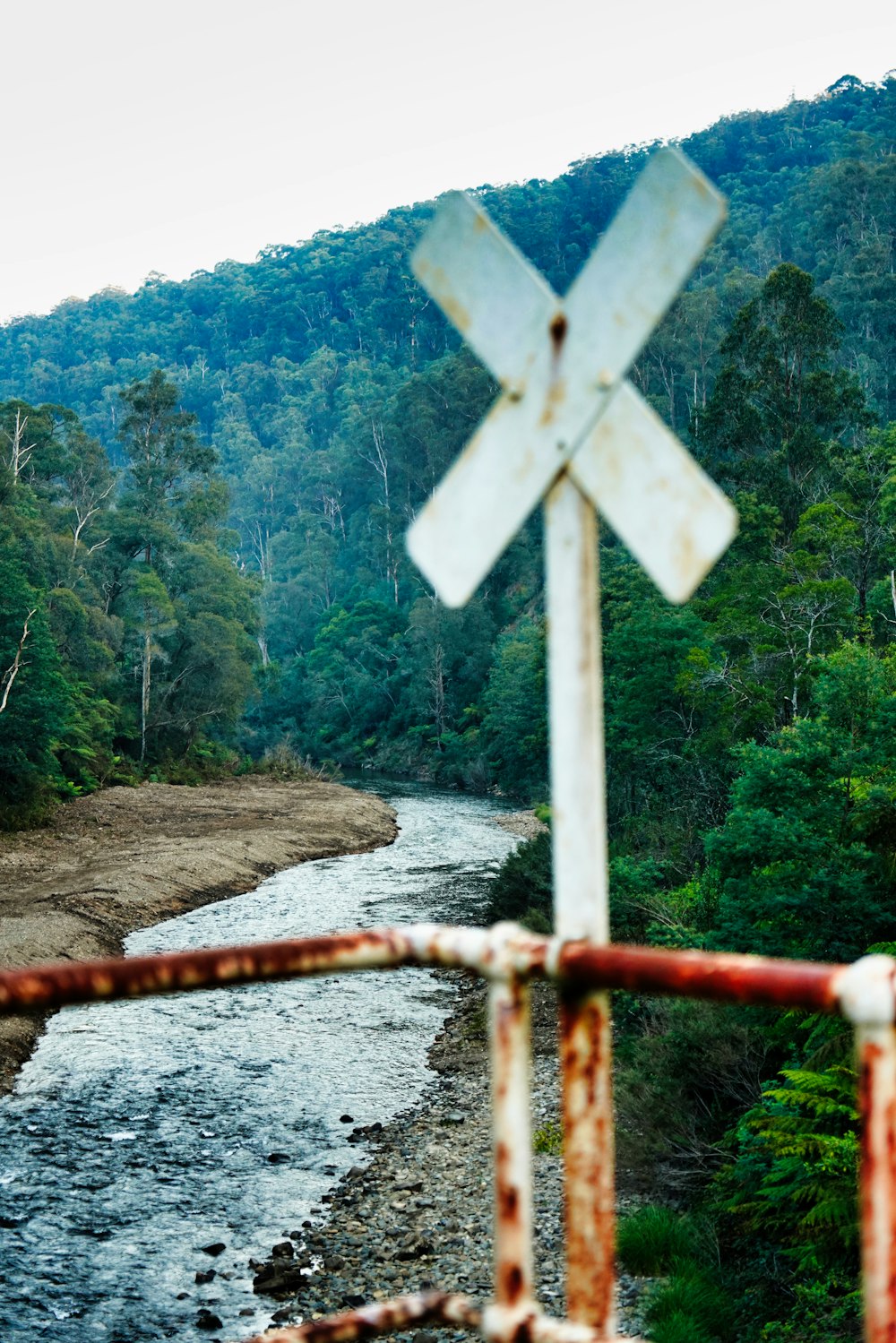 a rusted metal railing overlooks a river and forest