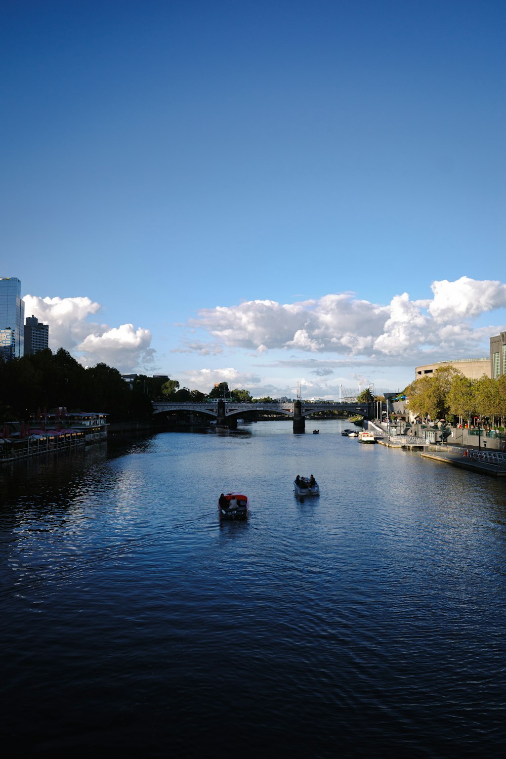 two boats floating down a river next to tall buildings