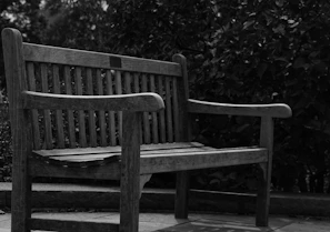 An outdoor teak bench set against a lush garden backdrop, showcasing natural durability and beauty