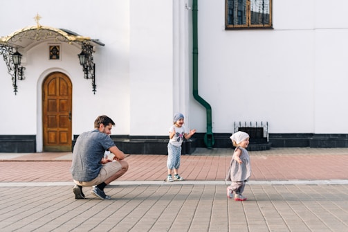 A Muslim father playing soccer with his young sons in a sunny park, laughter and joy in the air.