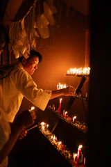 A serene priest lighting a golden diya inside an ancient temple surrounded by traditional decorations.
