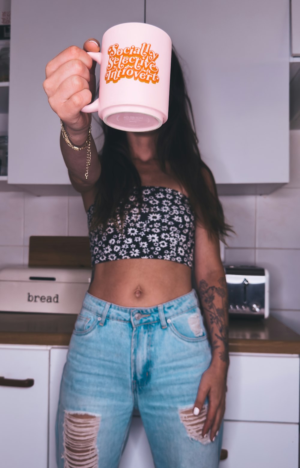 a woman in ripped jeans holding a coffee mug