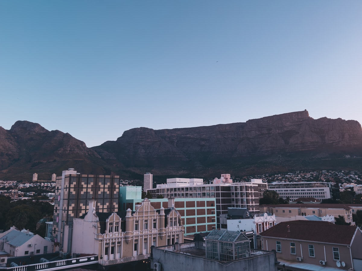 The roofs and buildings of Cape Town, with the flat ridge of Table Mountain rising behind them under a soft sky