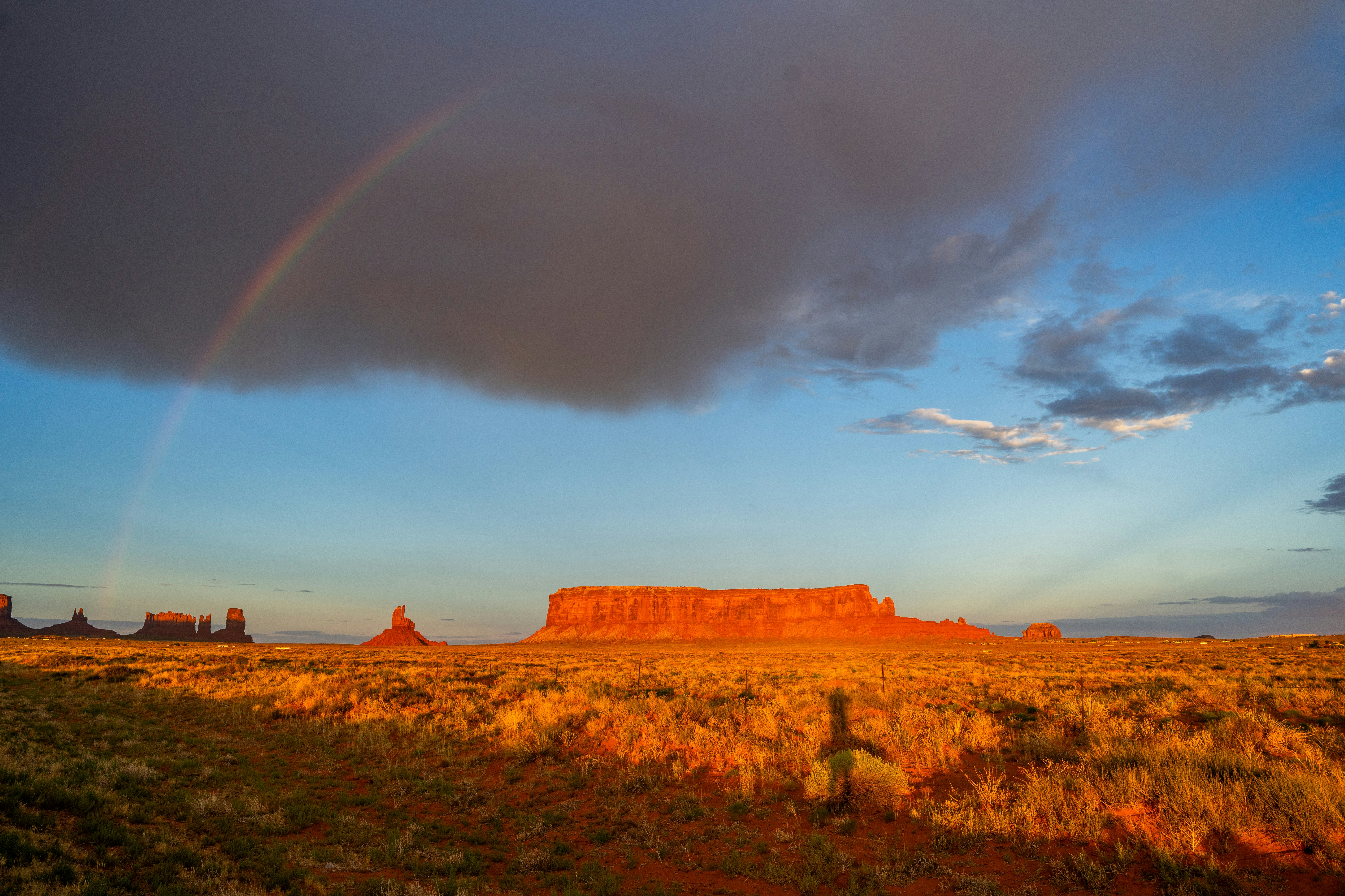 a rainbow in the sky over a desert landscape