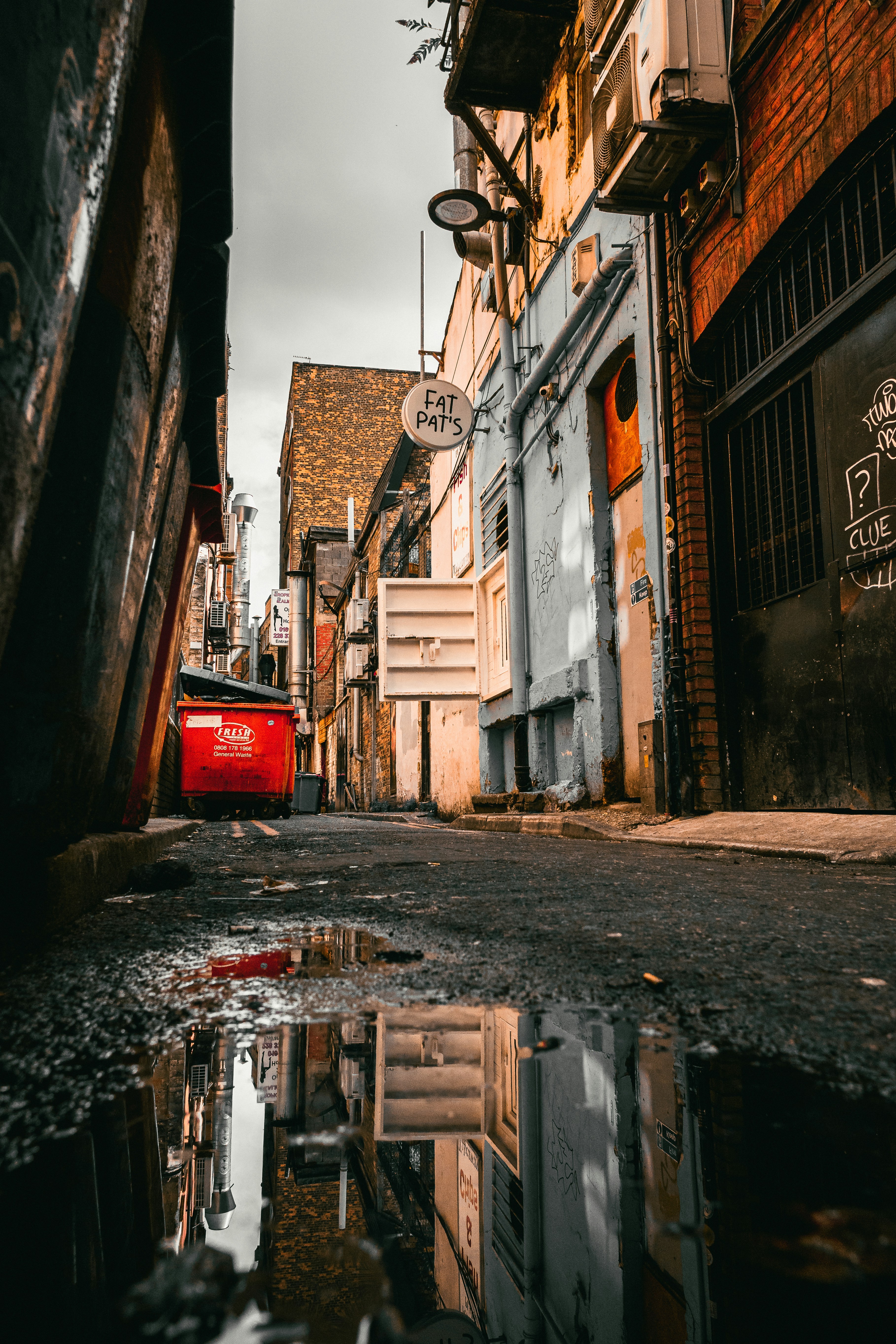 A street with a puddle of water in the middle of it photo – Free Street ...